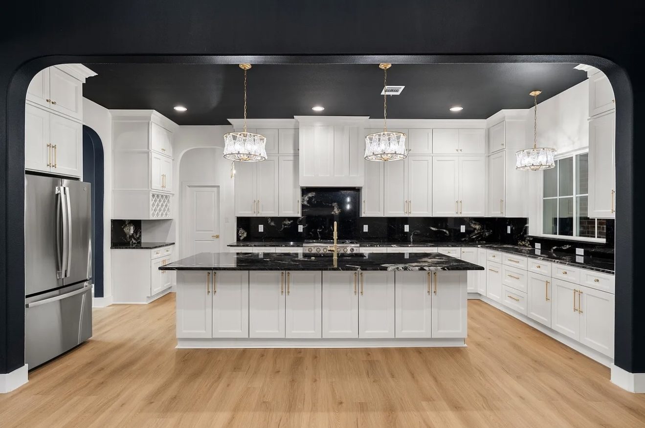 Renovated kitchen with white cabinetry and black granite